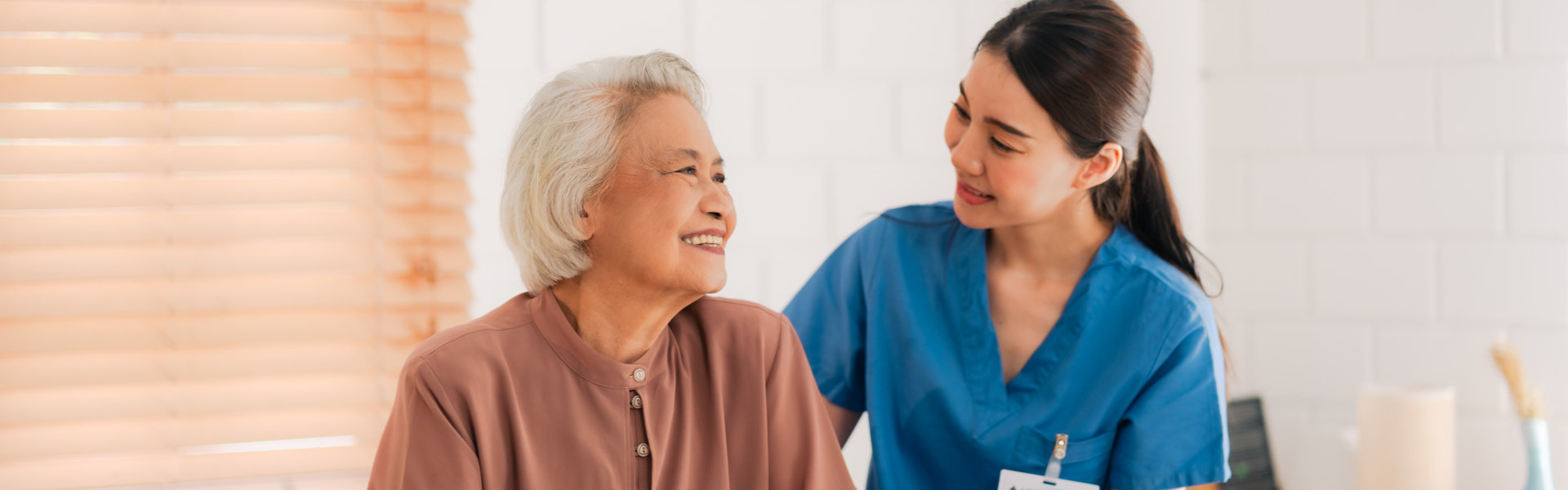 aide and senior woman smiling at each other